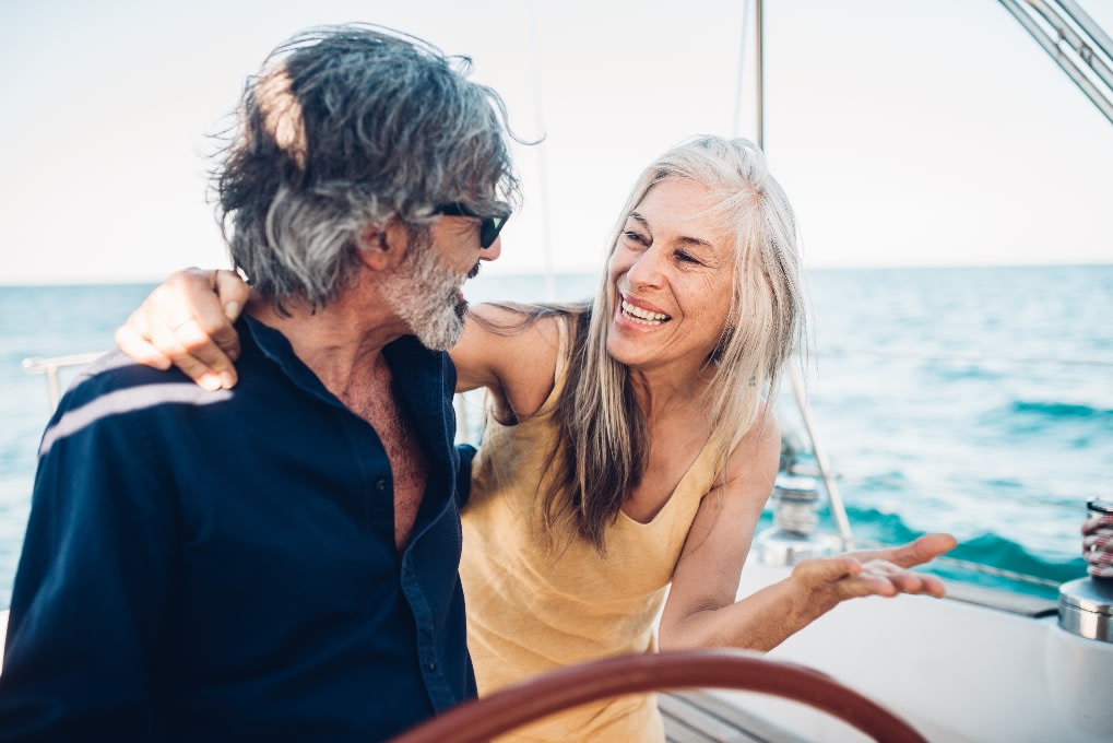 A smiling adult couple on a boat with their arms around each other